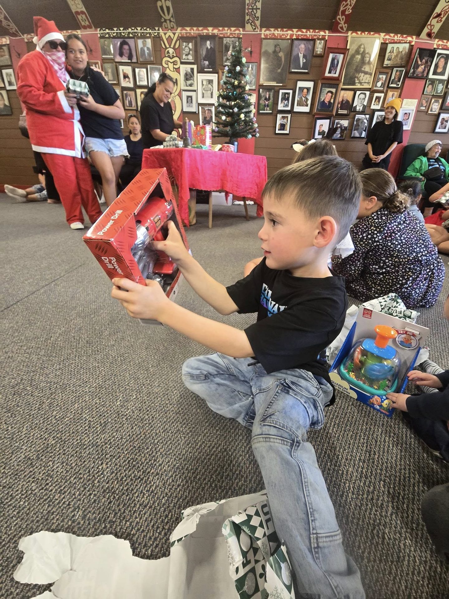 Tamariki opening their gifts at the marae Christmas celebration