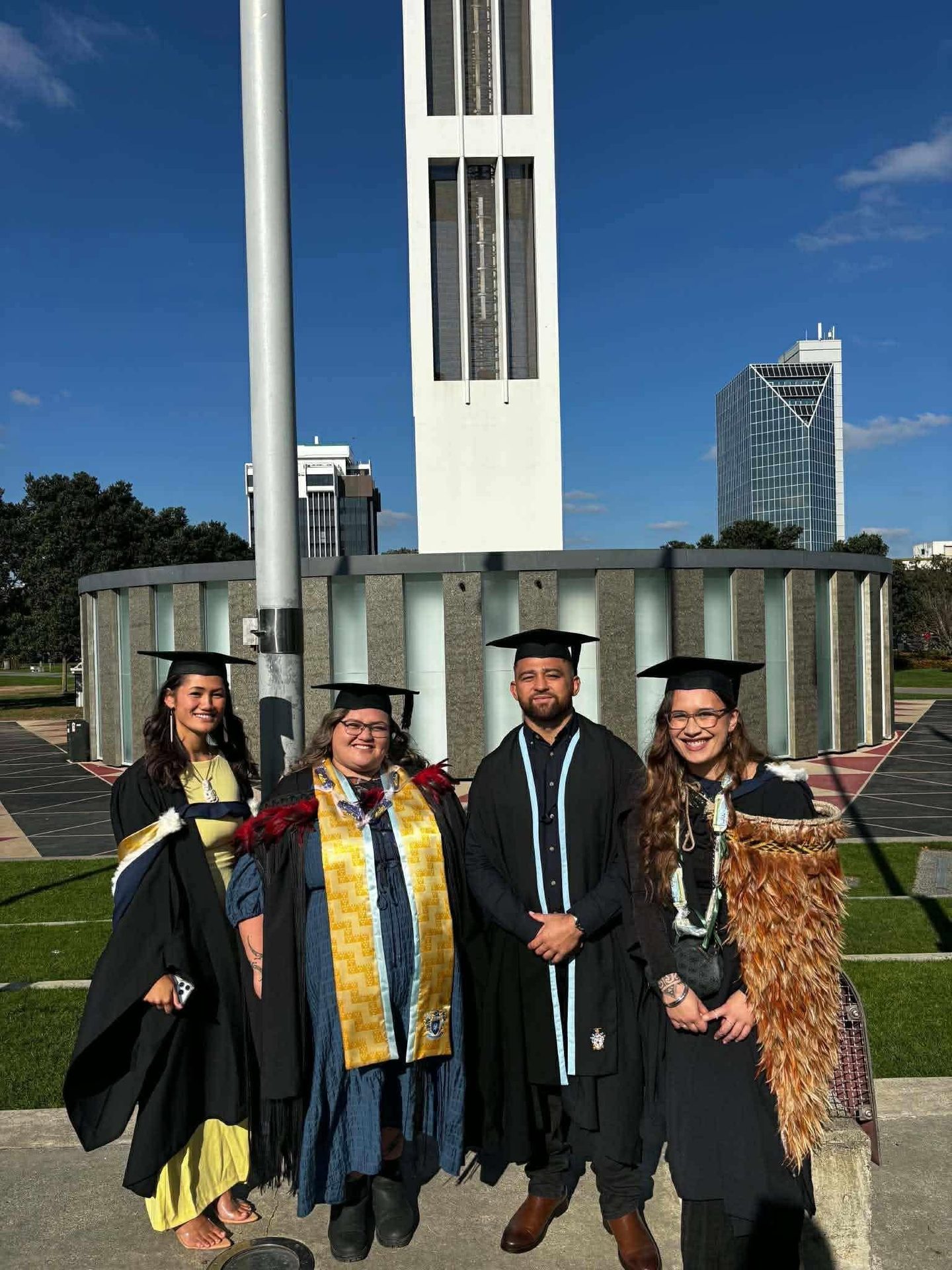 Four graduates in regalia, smiling with pride