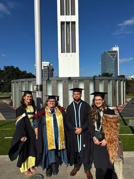 Four whānau graduates in their graduation attire, smiling with pride