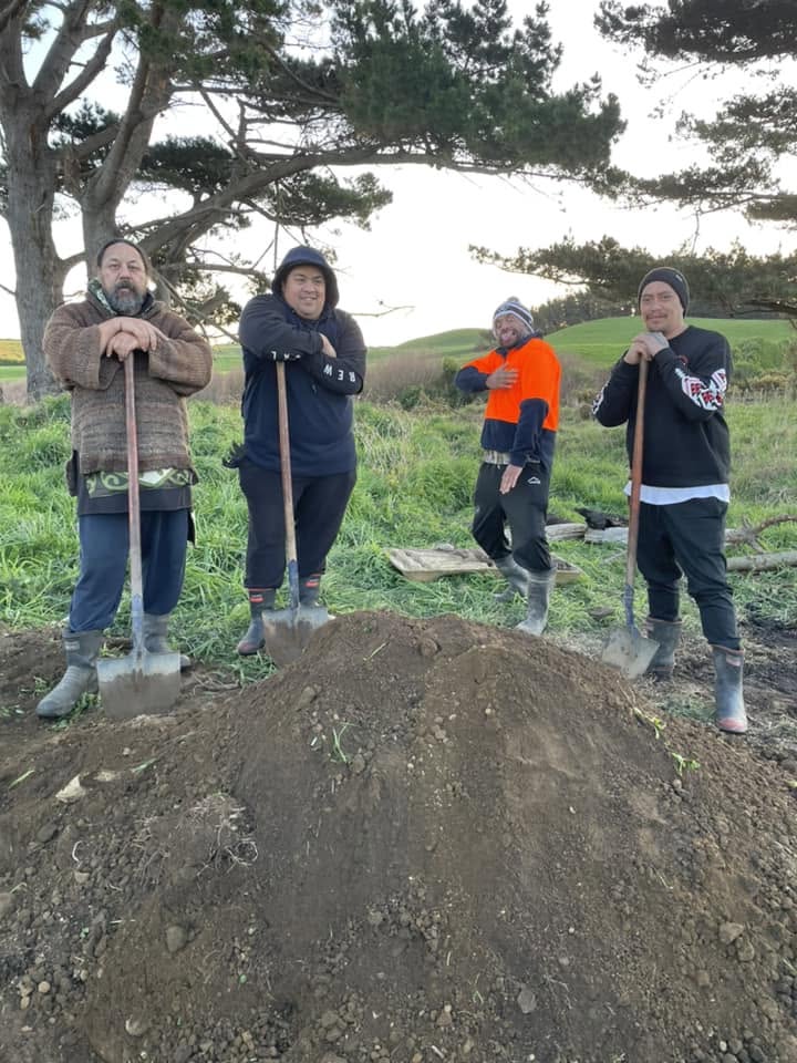 A crew of men at work by the hangi pit.