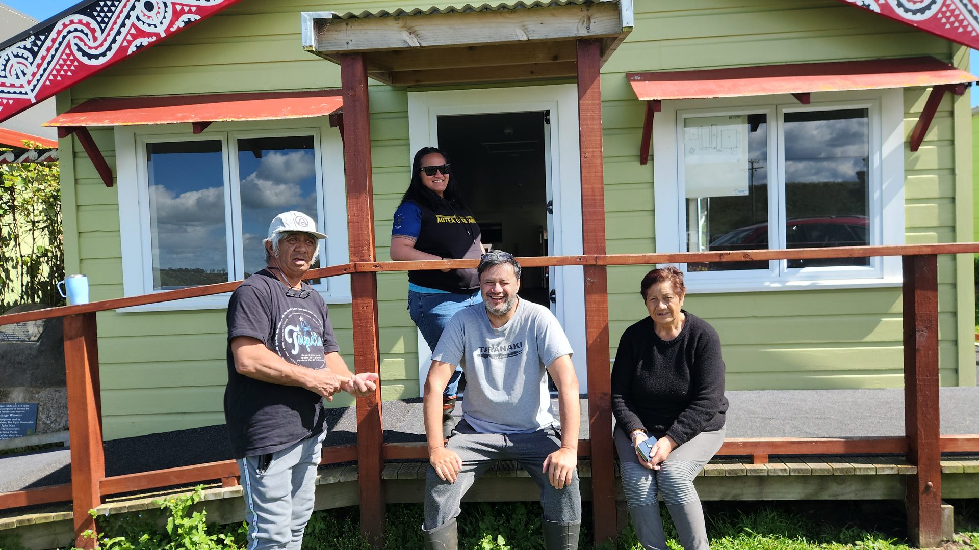 Smiling whānau on the verandah of the Putoetoe wharekai