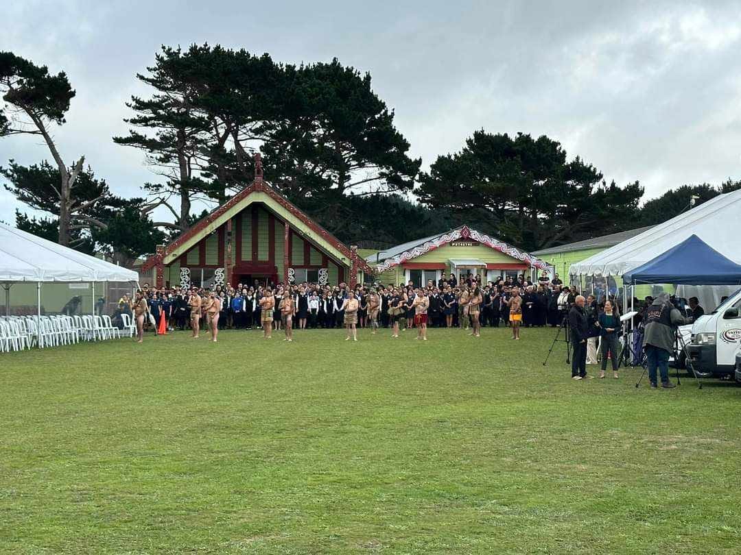 Whānau and manuhiri gathered in front of Taiporohēnui wharenui
